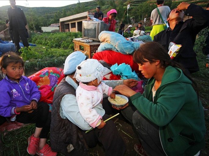 This picture taken on July 22, 2013 shows survivors eating instant noodles on a clearing after their homes were damaged in the earthquake-hit township of Majiagou in Minxian county in Dingxi, in northwest China's Gansu province. Rescuers battled through dusty rubble on July 23 to try to reach victims after two shallow earthquakes hit China, killing at least 89 people.