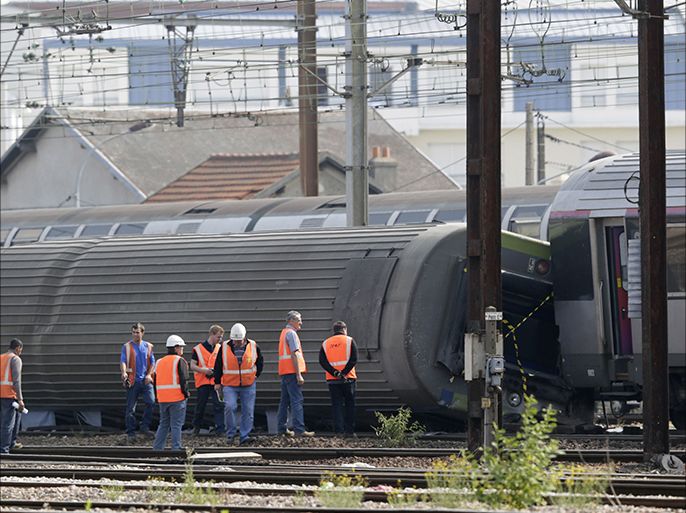 Investigators inspect derailed cars on the site of a train accident in the railway station of Bretigny-sur-Orge on July 13, 2013 near Paris. Rescue workers searched for survivors early Saturday, hours after a high-speed train derailed just south of Paris, killing at least six people and injuring 30 more. AFP PHOTO / KENZO TRIBOUILLARD