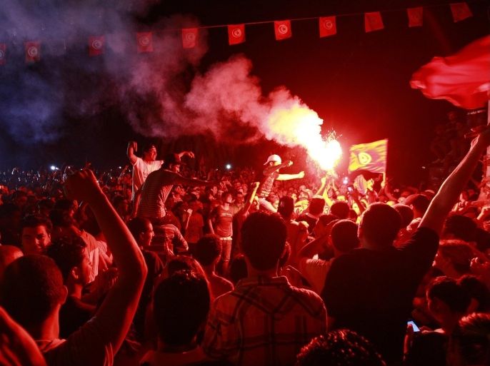A demonstrator holds a lighted flare during a protest to demand the ouster of the Islamist-dominated government, outside the Constituent Assembly headquarters in Tunis July 28, 2013.