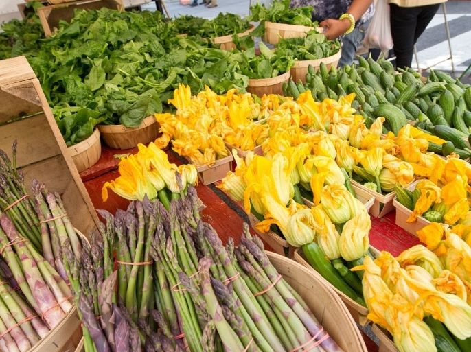 A woman checks out various produce, lettuce, asparagus and zucchini on May 2, 2013 at the farmers market near the White House in Washington, DC.