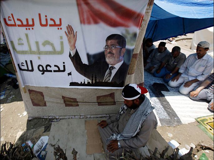 Members of the Muslim Brotherhood and supporters of deposed Egyptian President Mohamed Mursi perform afternoon prayers at the Rabaa Adawiya square, where they are camping at, in Cairo July 11, 2013. Political infighting threatened to stall Egypt's transition plans on Thursday, as the military cracked down on Muslim Brotherhood leaders it blames for inciting a clash in Cairo in which troops shot and killed 53 protesters. Monday's violence between supporters of Mursi, Egypt's first freely elected leader toppled by the army last week, and soldiers at a military compound has opened deep fissures in the Arab world's most populous country. The banner reads, "We still love you every where". REUTERS/Amr Abdallah Dalsh (EGYPT - Tags: POLITICS CIVIL UNREST RELIGION)
