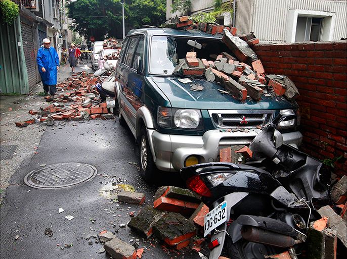 A man walks past bricks scattered over vehicles, after a brick wall was blown over by strong winds from Typhoon Soulik, in Taipei July 13, 2013. Typhoon Soulik brought powerful winds and heavy rain as it landed in Taiwan early Saturday, killing one and injuring 21, local media said. REUTERS/Pichi Chuang (TAIWAN - Tags: ENVIRONMENT DISASTER TRANSPORT)