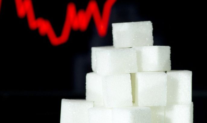 A picture taken on January 10, 2013 in Paris shows an illustration made with pieces of white sugar and a screen displaying the sugar exchange rate curve from 2002 to 2012.