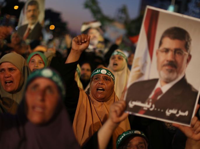 TOPSHOTSEgyptian supporters of the Muslim Brotherhood shout slogans in favour of Egypt's deposed president Mohamed Morsi (portrait) after breaking the fast outside Cairo's Rabaa al-Adawiya mosque on July 10, 2013, the first day of Islam's holy month of Ramadan. Tens of millions across the Muslim world fast from dawn to dusk and strive to be more pious and charitable during the month, which ends with the eid holiday.