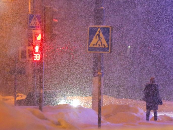 epa03640585 A Russian woman waits at traffic lights during a heavy snowfall in Podolsk outside Moscow, Russia, 25 March 2013. Reports state that the amount of fallen snow during this winter has reached three meters, which is twice the usual amount and temperatures are almost 10 degrees lower than normal. EPA/MAXIM SHIPENKOV
