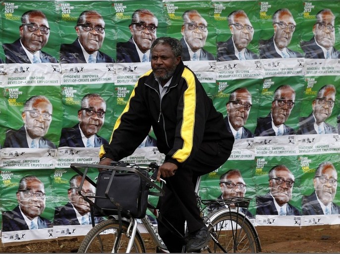 A man rides a bicycle past election posters of Zimbabwe's President Robert Mugabe in Harare July 30, 2013. Heavily armed riot police deployed in potential election flashpoints in Zimbabwe on Tuesday on the eve of a poll showdown between Mugabe and Prime Minister Morgan Tsvangirai that remains too close to call.