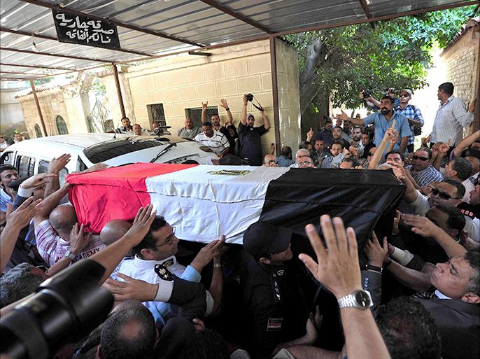 Mourners carry the coffin of Egyptian police officer Colonel Mohammed Hani, who was killed by six bullets to the head when unknown gunmen opened fire on him with machine guns in an ambush in the Sinai town of El-Arish, during his funeral procession two days after the incident on July 1, 2013 in Egypt's northern coastal city of Alexandria. The ambush in El-Arish is the second attack on police in the restive region this month. AFP PHOTO / STR