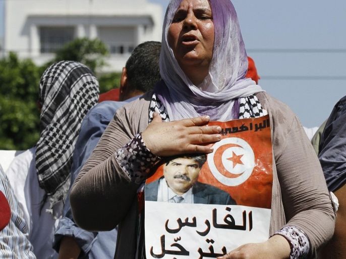 Mbarka Brahmi, wife of slain Tunisian opposition politician Mohamed Brahmi, holds a poster of her husband during his funeral procession towards the nearby cemetery of El-Jellaz, where he is to be buried, in Tunis July 27, 2013. Tens of thousands of Tunisians turned out for Brahmi's funeral on Saturday, and called for the Islamist-led government to be toppled.