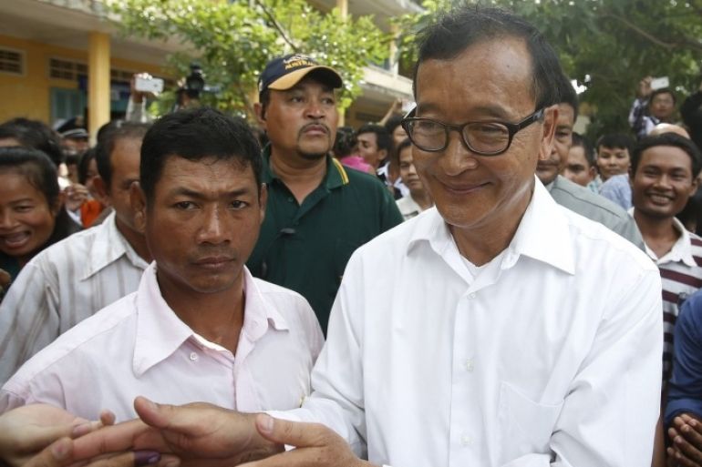 Sam Rainsy (C), president of the Cambodia National Rescue Party (CNRP), visits a polling station during the general elections at a pagoda in Phnom Penh July 28, 2013. The Cambodian People's Party (CPP) of long-serving Prime Minister Hun Sen won Sunday's election, taking 68 seats to the main opposition party's 55, the government's main spokesman said.