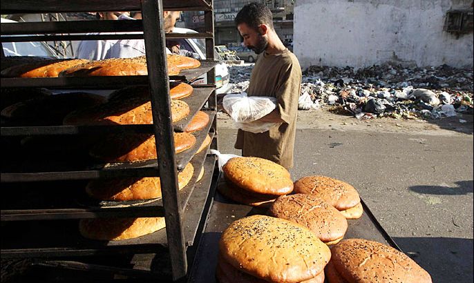 A man holds bread as he walks along a street full of debris before the time for iftar, or breaking fast, during the Islamic holy month of Ramadan in the city of Aleppo July 13, 2013. REUTERS/Muzaffar Salman (SYRIA - Tags: FOOD RELIGION SOCIETY