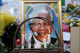 Candels are seen burning by a portrait of Nelson Mandela outside of the Mediclinic Heart hospital in Pretoria on July 6, 2013 where former South African president Nelson Mandela lays in critical condition. Emotional crowds gathered outside the hospital, as relatives and clan elders made preparations for the revered former South African leader's final journey. Singing supporters amassed outside the Pretoria hospital where the 94-year-old anti-apartheid hero was fighting for his life. AFP PHOTO / Filippo MONTEFORTE