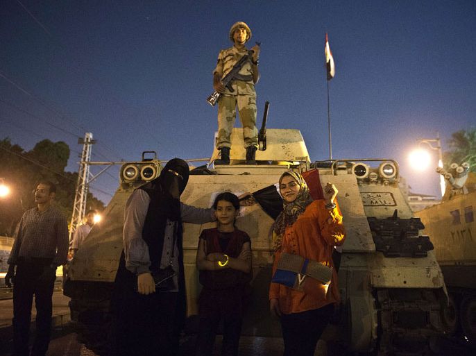 KLD861 - Cairo, -, EGYPT : Women pose for a picture in front of an armoured vehicle with a soldier standing on it outside the presidential palace in Cairo on July 19, 2013, while opponents of ousted president Mohamed Morsi gather to celebrate the 40th anniversary of the six day war against Israel. AFP PHOTO / KHALED DESOUKI
