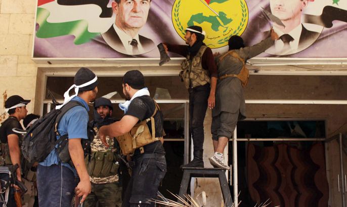 Rebel fighters tear down a poster bearing the portrait of Syrian President Bashar al-Assad (R) and his late father and predecessor Hafez al-Assad (L) in Syria's eastern town of Deir Ezzor, on August 10, 2013. The United Nations says that more than 100,000 people have been killed since, and millions have been displaced or fled the country. AFP PHOTO/ABO SHUJA