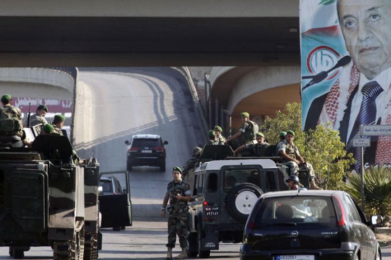Lebanese army troops patrol the airport highway on the southern outskirts of Beirut on August 9, 2013, following the kidnapping by gunmen early in the morning of two pilots working for Turkish Airlines on the road leading to the airport, according to Lebanon's Interior Minister Marwan Charbel. Portrait on Amal movement billboard shows Lebanese Parliament Speaker Nabih Berri, who heads the Shiite movement. AFP PHOTO