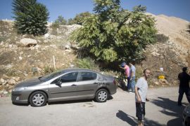 Palestinians look a damages car with anti-Arab graffiti written on it in Hebrew in the Arab village of Beit Safafa, in the southern outskirts of Jerusalem, on August 27, 2013. Vandals slashed the tyres of six cars and some had been spray-painted with the words in Hebrew reading: "price tag" and "revenge" in the Arab neighbourhood overnight. "Price tag" attacks are the name used for Jewish extremist hate crimes that generally target Arabs, but have also extended to Christian places of worship. AFP PHOTO/MENAHEM KAHANA
