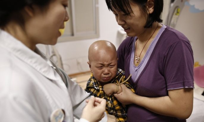 Four-year-old Niuniu, who has late-stage neuroblastoma, a malignant cancer of the nervous system, cries after receiving a prep injection for his CT scan at the Shanghai Children's Hospital in Shanghai, May 30, 2013. China has massively ramped up spending on health care, but many millions of people still cannot afford even basic health care, and health insurance schemes run by the government have only patchy coverage. Picture taken May 30, 2013.