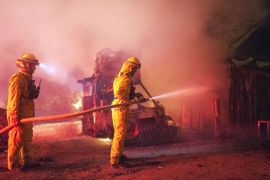 epa03790127 A picture made available on 16 July 2013 shows firefighters from CalFire work to put out flames on an outbuilding near Apple Canyon Rd in Mountain Center, California, USA, 15 July 2013 as the mountain fire grew to 4700 acres overnight. At least two buildings were destroyed along with multiple outbuildings as crews struggled with rough terrain and erratic winds to get a control on the blaze, which started Monday afternoon. EPA/STUART PALLEY