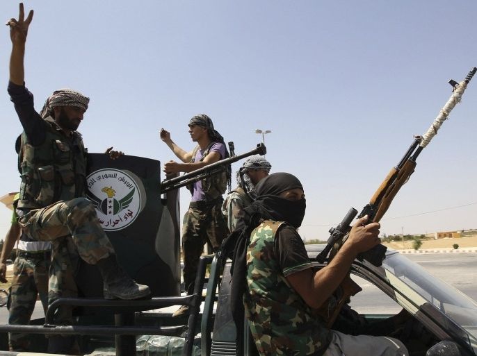 Members of 'Free Men of Syria' (Ahrar Suriya) brigade, operating under the Free Syrian Army, gesture and hold their weapons as they head in a convoy to Sadd al-Shouhadaa on the Euphrates river in the eastern countryside of Aleppo to declare the formation of the Eastern Front August 18, 2013.
