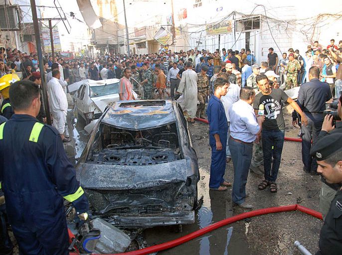 A picture taken on August 19, 2013 shows Iraqis gathering near the remains of vehicles at the scene of a car bomb explosion in Nasiriyah, south of the Iraqi capital Baghdad. Attacks on August 19, that were concentrated in Mosul, a predominantly Sunni Arab city, killed six people in Iraq, as gunmen defied massive government operations to stem some of the worst violence to have hit the country in five years. AFP