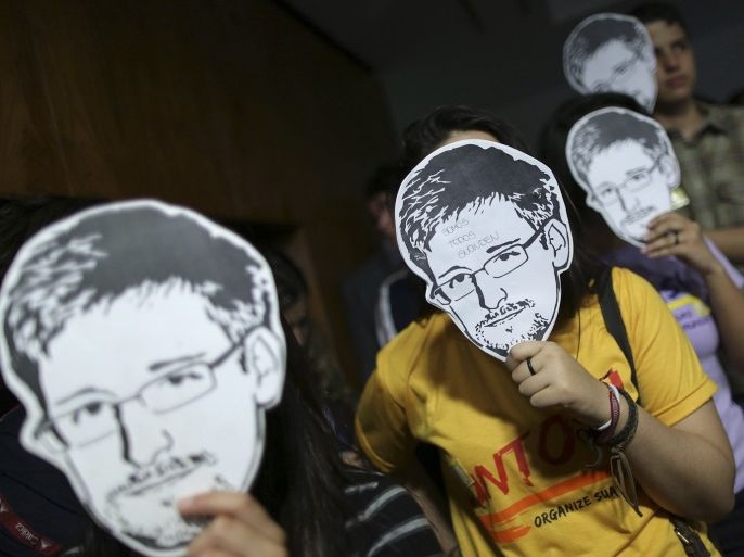 People use masks with pictures of former NSA contractor Edward Snowden masks during the testimonial of Glenn Greenwald, the American journalist who first published the documents leaked by Snowden, before a Brazilian Congressional committee on NSA's surveillance programs, in Brasilia August 6, 2013.