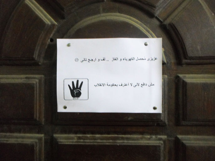 لافتة ملعقة على باب شقة تفيد بامتناع صاحبها عن دفع الفواتير (الجزيرة نت)