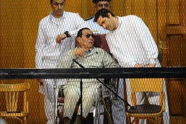 Egyptian toppled president Hosni Mubarak and his two sons Alaa (L) and Gamal stand behind bars during their trial at the Police Academy on September 14, 2013 in Cairo. Mubarak appears in court for the second time since his release from Cairo's Tora prison and he faces an array of charges, including complicity in the deaths of some 850 people killed in the Arab Spring-inspired uprising against him, and corruption. AFP PHOTO / AHMED EL-MALKY