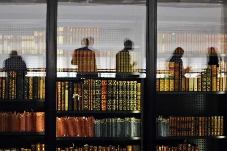 In this photo taken Wednesday, April 3, 2013, people are reflected in the windows of the British Library where old books are kept in London, Wednesday, April 3, 2013. Capturing the unruly, ever-changing Internet is like trying to pin down a raging river. But the British Library is going to try. For centuries the library has preserved a copy of every book, pamphlet, magazine and newspaper published in Britain. Starting Saturday, April 6, 2013, it will also be bound to record every website, e-book and blog, in a bid to preserve the nation's "digital memory."