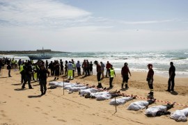 Rescue workers stand next to bodies of migrants who drowned lie on the beach in the Sicilian village of Sampieri September 30, 2013. At least 13 people on a migrant boat arriving in Sicily drowned close to the coast near the eastern city of Ragusa, apparently after trying to disembark from their stranded vessel, Italian authorities said on Monday. Officials said the boat was carrying around 250 people but there was no immediate word on where they came from.