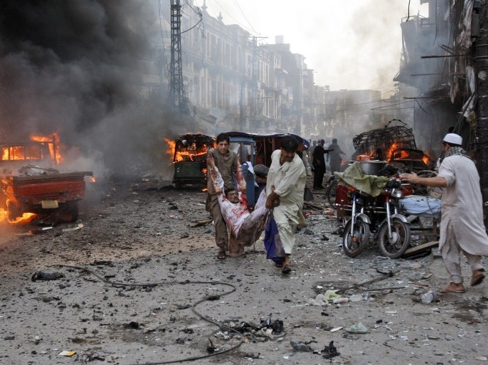 Pakistani men carry an injured man away from the site moments after a car bomb attack in Peshawar, Pakistan, Sunday, Sept. 29, 2013. A deadly car bomb exploded on a crowded street in northwestern Pakistan Sunday, in the third blast to hit the troubled city of Peshawar in a week, officials said.