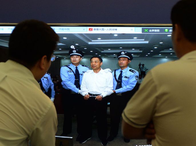 MRR2015 - Jinan, Shandong, CHINA : Staff look at an image of disgraced politician Bo Xilai at the Intermediate People's Court after being sentenced to life in prison when his verdict was announced in Jinan, Shandong Province on September 22, 2013. Fallen Chinese political star Bo Xilai was sentenced by a court to life in prison, following a sensational scandal that culminated in the country's highest-profile trial in decades. AFP PHOTO