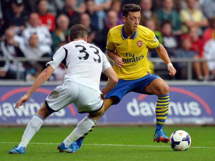 Arsenal's German midfielder Mesut Ozil (L) controls the ball from Swansea City's Welsh defender Ben Davies during the English Premier League football match between Swansea City and Arsenal at The Liberty Stadium in Swansea, south Wales on September 28, 2013. AFP PHOTO/Paul Ellis - RESTRICTED TO EDITORIAL USE. NO USE WITH UNAUTHORIZED AUDIO, VIDEO, DATA, FIXTURE LISTS, CLUB/LEAGUE LOGOS OR “LIVE” SERVICES. ONLINE IN-MATCH USE LIMITED TO 45 IMAGES, NO VIDEO EMULATION. NO USE IN BETTING, GAMES OR SINGLE CLUB/LEAGUE/PLAYER PUBLICATIONS.