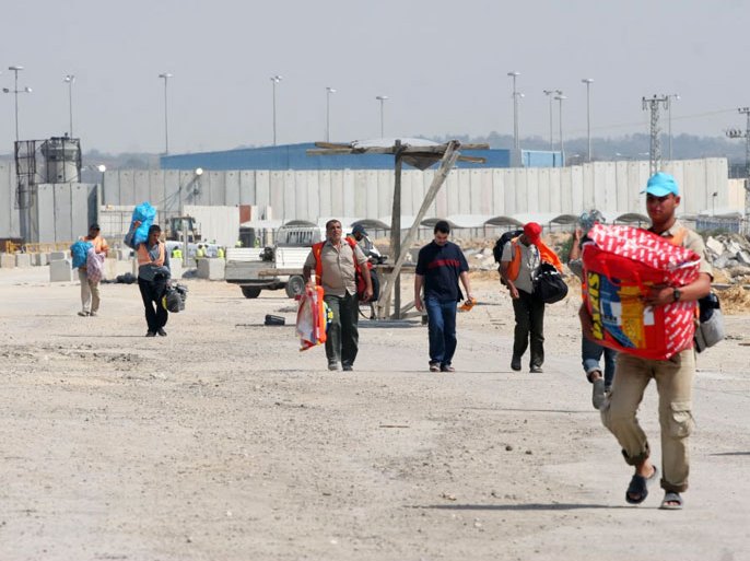 عمال يحملون شنط العائدين من معبر بيت حانون –إيرز- إلى غزة