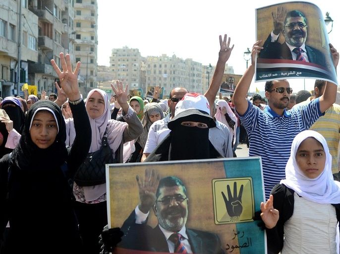 Supporters of Egypt's ousted Islamist president Mohamed Morsi hold his portrait and flash a four finger symbol, known as 'Rabaa', which means four in Arabic, to remember those killed in the crackdown on the Rabaa al-Adawiya protest camp in Cairo earlier in the year, as they take part in a demonstration against the military on September 20, 2013 along the seafront in the northern coastal city of Alexandria. Egypt's army-backed authorities arrested the spokesman of the Muslim Brotherhood on September 17 and froze the assets of other Islamists, in a new blow to deposed president Mohamed Morsi's supporters.