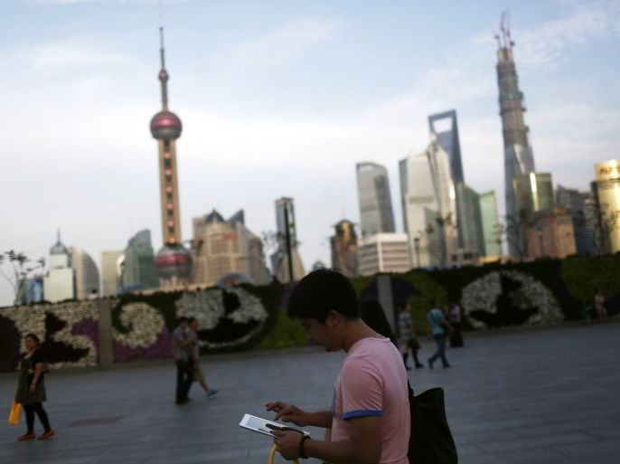 A man checks his iPad on the Bund in front of the financial district in Shanghai September 24, 2013. Facebook, Twitter and other websites deemed sensitive and blocked by the Chinese government will be accessible in a planned free-trade zone (FTZ) in Shanghai, the South China Morning Post reported on Tuesday.