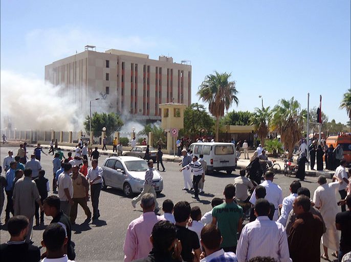 Bystanders gather at the scene as smoke rises from an Egyptian provincial police headquarters in al-Tur, in the southern part of Egypt's Sinai peninsula, on October 7, 2013, following a car bomb explosion which killed three policemen. Suspected militants killed nine people in attacks in Egypt today, a day after clashes between Islamists and police left dozens dead and dashed hopes of restored calm after president Mohamed Morsi's ouster. AFP PHOTO/STR