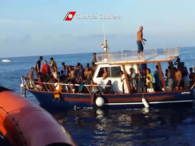 COS12 - Lampedusa, -, ITALY : This picture grabbed on a video released by the Guardia Costiera on October 4, 2013 shows immigrants on a boat after their rescue near Lampedusa on October 3. Italy today mourned the 300 African asylum-seekers feared dead in the worst ever Mediterranean refugee disaster, as the government appealed for Europe to stem the influx of migrants. As the grim search for bodies off the island of Lampedusa continued, an emotional Pope Francis said Friday should be "a day of tears" for a "savage world" that ignored the plight of refugees. Emergency services on the remote island -- Italy's southernmost point -- said they had recovered 111 bodies so far and rescued 155 survivors from a boat with an estimated 450 to 500 people on board.