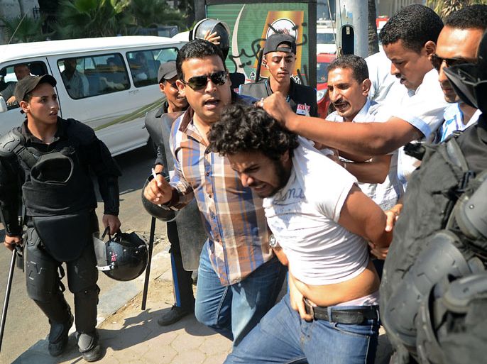 EGYPT : Egyptian police detain a political activists and supporter of 28-year-old blogger Khaled Said who died following police questioning before the revolution in 2010, during clashes with police outside a court in Egypt's northern coastal city of Alexandria on October 1, 2013 during the trial of Egyptian police officers Awad Ismail Suleiman and Mahmud Salah Amin accused of using excessive force and killing Said. The death of the Egyptian youth sparked demonstrations in Egypt, in the most high profile case to have dominated the headlines at the time. AFP PHOTO / STR