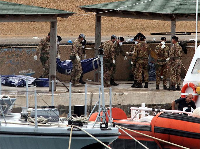 epa03900727 Italian military personnel disembark from a boat carrying the bodies of African migrants killed in a shipwreck off the Italian coast lie in Lampedusa harbour, Lampedusa, Italy, on 07 October 2013. The search for bodies continues off the coast of southern Italy as the death toll of African migrants who drowned as they tried to reach the island of Lampedusa is expected to reach over 300 people. The tragedy has bought fresh questions over the thousands of asylum seekers that arrive into Europe by boat each year. EPA/CORRADO LANNINO