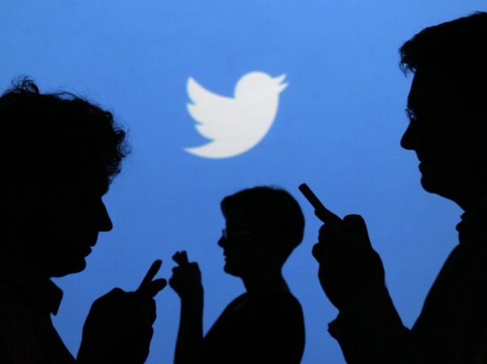 People holding mobile phones are silhouetted against a backdrop projected with the Twitter logo in this illustration picture taken in Warsaw September 27, 2013. REUTERS/Kacper Pempel