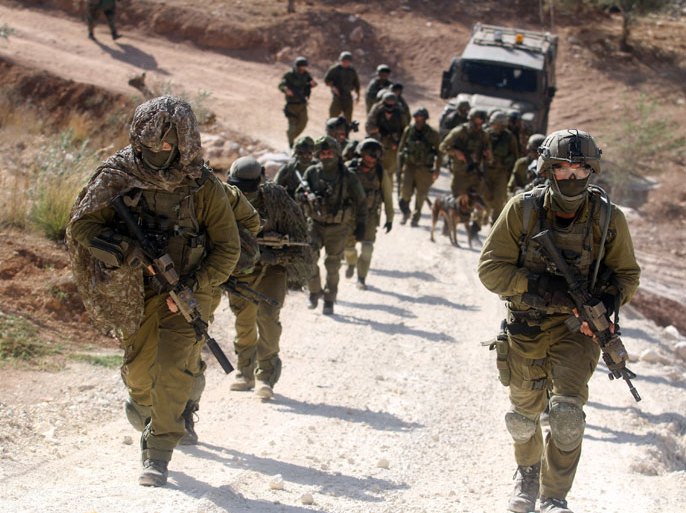XAG687 - BILIN, WEST BANK, - : Israeli soldiers march up a hill following a fire fight in which a Palestinian man they named as Mohammed Assi was killed, on October 22, 2013, in the area between the West Bank villages of Bilin and Kufr Ne'meh, 10 kilometres (six miles) northwest of Ramallah. The army confirmed the incident, naming the dead man as Mohammed Assi and describing him as an Islamic Jihad militant responsible for the November 2012 bombing of a Tel Aviv bus that wounded 29 people. AFP PHOTO/ISSAM RIMAWI