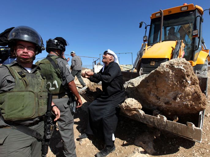 epa03372425 A Palestinian Bedouin pleads with Israeli border police as shacks and tent structures are demolished by tractors near the Jewish settlement of Sosia, near Yatta in the southern West Bank, 28 August 2012. Bedouin tents and shacks were demolished while Israeli Border Police prevented bedouins from stopping the tractors. The shacks were located in the so-called Area C, a closed military zone where Israel exercises full control. EPA/ABED HASHLAMOUN