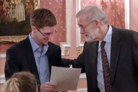 An image grab taken from a video released by Wikileaks on October 12, 2013 shows US intelligence leaker Edward Snowden (L) receiving an award from former CIA analyst Ray McGovern during a dinner with US ex-intelligence workers and activists in Moscow on October 9, 2013. Snowden warned of dangers to democracy in the first video released of the fugitive since Russia granted him temporary asylum in August. AFP PHOTO / WIKILEAKS