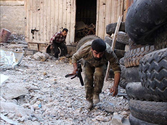 A member of the 'Al-Sultan Murad' brigade, operating under the Free Syrian Army, carries his weapon as he moves along piled tyres used as protection from snipers loyal to Syria's president Bashar al-Assad, in Aleppo's Bustan al-Basha district October 28, 2013. REUTERS/Molhem Barakat (SYRIA - Tags: CIVIL UNREST CONFLICT)