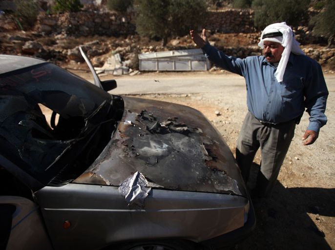 A Palestinian man gestures next to a vandalised car following a suspected Jewish extremist attack in the West Bank village of Burqa, east of Ramallah, on October 10, 2013, in an apparent revenge attack for the killing of an Israeli solider and evacuation of a settler outpost, police said. Police spokesman Micky Rosenfeld told AFP that "a number of suspects went into the village of Burqa and attempted to set fire to three vehicles". AFP PHOTO