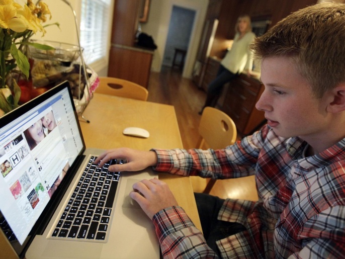 In this Oct. 24, 2013 photo, Mark Risinger, 16, checks his Facebook page on his computer as his mother, Amy Risinger, looks on at their home in Glenview, Ill. The recommendations are bound to prompt eye-rolling and LOLs from many teens but an influential pediatrician's group says unrestricted media use has been linked with violence, cyber-bullying, school woes, obesity, lack of sleep and a host of other problems. Marks mom said she agrees with restricting kids time on social media but that deciding on other media limits should be up to parents. (AP Photo/Nam Y. Huh)
