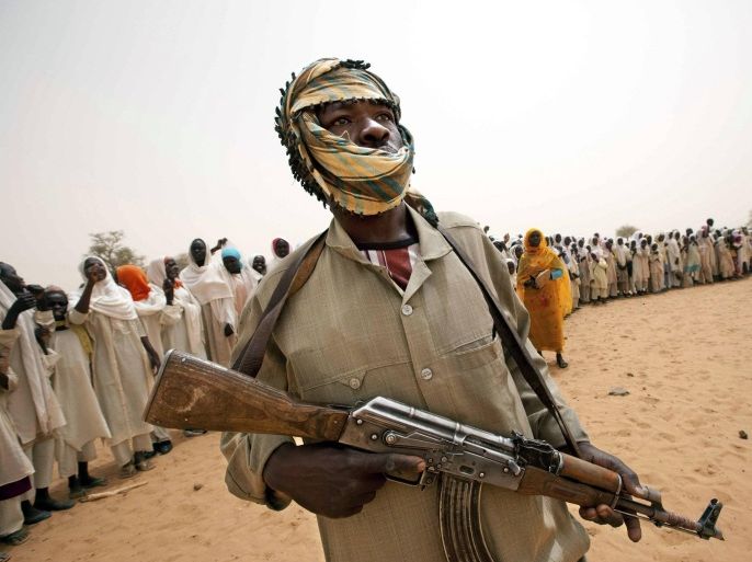 A member of the Abdul Wahid faction of the Sudan Liberation Army (SLA) rebel movement stands guard as people stand in line behind him for the arrival of an African Union-United Nations Mission in Darfur (UNAMID) delegation to open a new clinic in Forog, north Darfur in this May 30, 2012 file picture. REUTERS/Albert Gonzalez Farran/UNAMID/Handout via Reuters