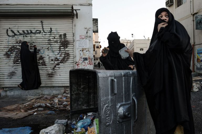 Bahraini women use debris to make noise on a turned over garbage bin as they shout an anti-regime slogans during clashes with security forces following an anti-regime protest in the village of Sanabis, west of Manama, on October 18, 2013. Shiites in the Sunni-ruled kingdom of Bahrain continue to demonstrate in villages outside the capital and frequently clash with police. Strategically located across the Gulf from Shiite Iran, Bahrain is home to the US Navy's Fifth Fleet and is an offshore financial and services centre for its oil-rich Arab neighbours. AFP PHOTO/MOHAMMED AL-SHAIKH