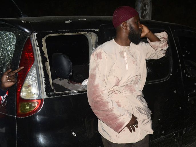 man who survived the drive-by shooting of Muslim cleric Sheikh Ibrahim Ismail stands next to a bullet-riddled car on the Mombasa-Malindi highway late on October 3, 2013. Gunmen in Kenya killed four people including the cleric linked to a radical mosque in the port city of Mombasa, police said. Sheikh Ibrahim Ismail was viewed as the successor to Aboud Rogo Mohammed, a controversial preacher accused of links to Somalia's Shebab insurgents, who was himself assassinated in a drive-by shooting in August 2012. AFP PHOTO/STR
