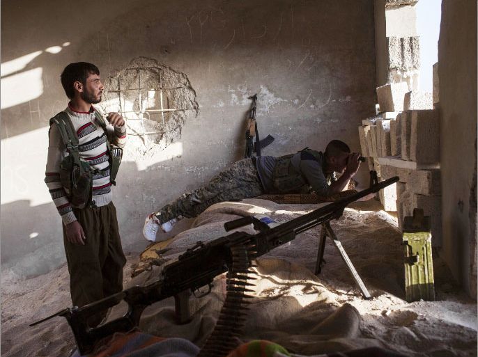 Armed fighters of the Committees for the Protection of the Kurdish People (YPG) hold a position in a building on October 16, 2013 in the Syrian town of Ras al-Ain, close to the Turkish border. At least 41 fighters have been killed in violent clashes pitting Kurds against jihadists and Islamist rebels in northeastern Syria, a monitoring group said on October 16, 2013. AFP PHOTO STR