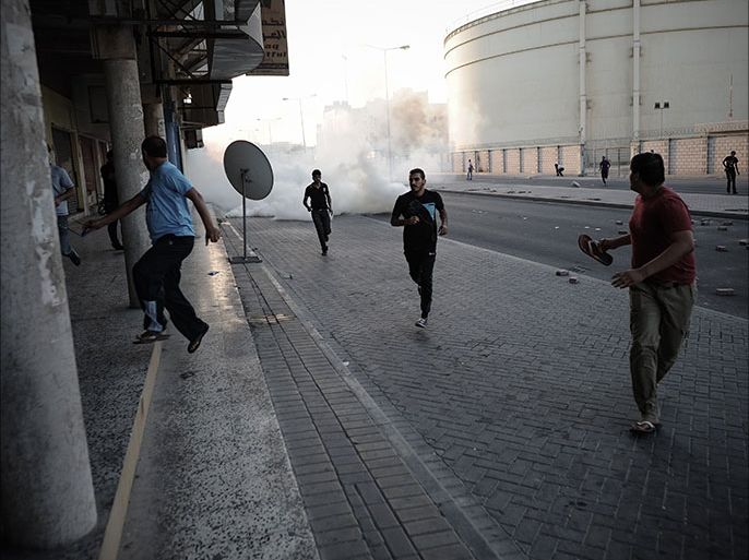 Bahraini protestors run for cover from tear gas and bird shots fired by riot police during clashes following the funeral of Hussain Mahdi Habib in the village of sitra, south of Manama, on October 20, 2013. Habib, 20, a political prisoner who escaped from prison on May 19, was found the day before after he was allegedly shot dead near Al Malkiyah coastal village. AFP PHOTO/MOHAMMED AL-SHAIKH